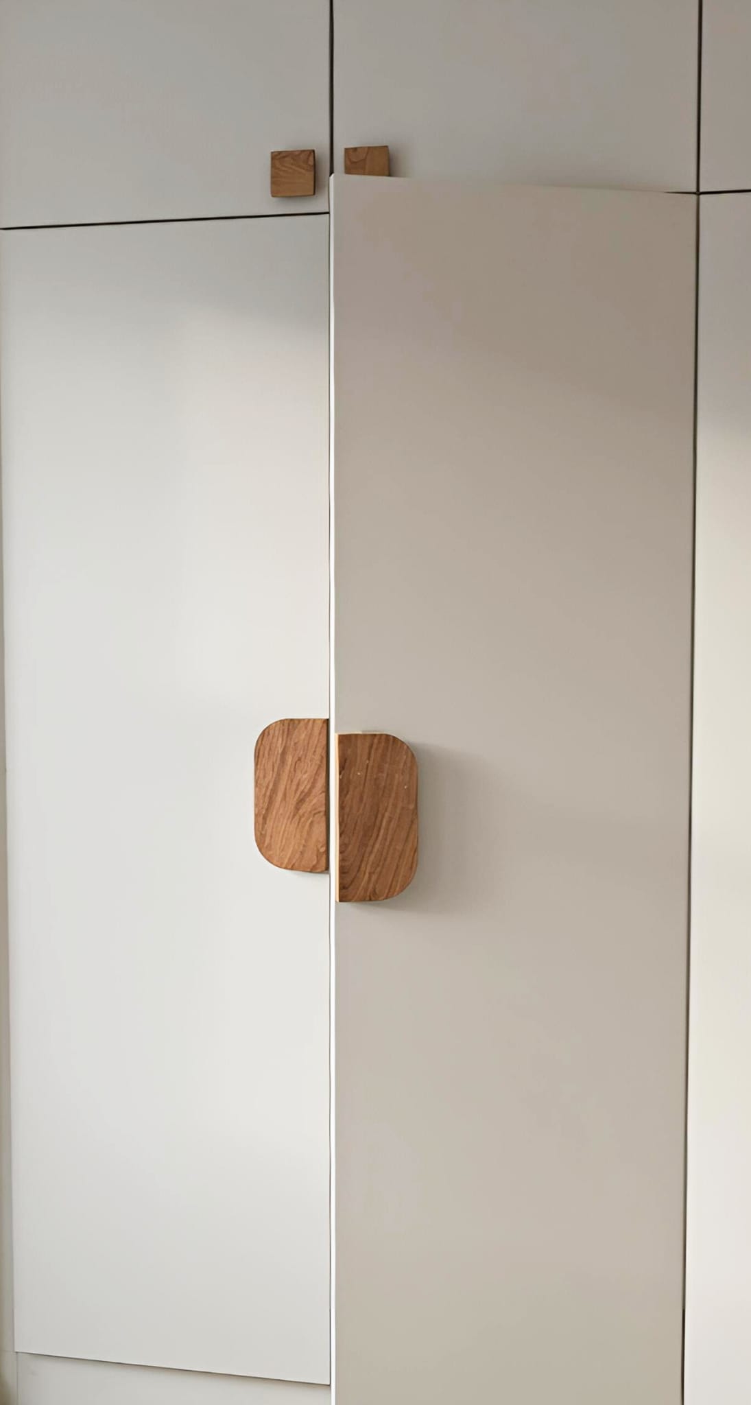 Rounded natural oak handles on off-white fitted wardrobe doors in Hackney