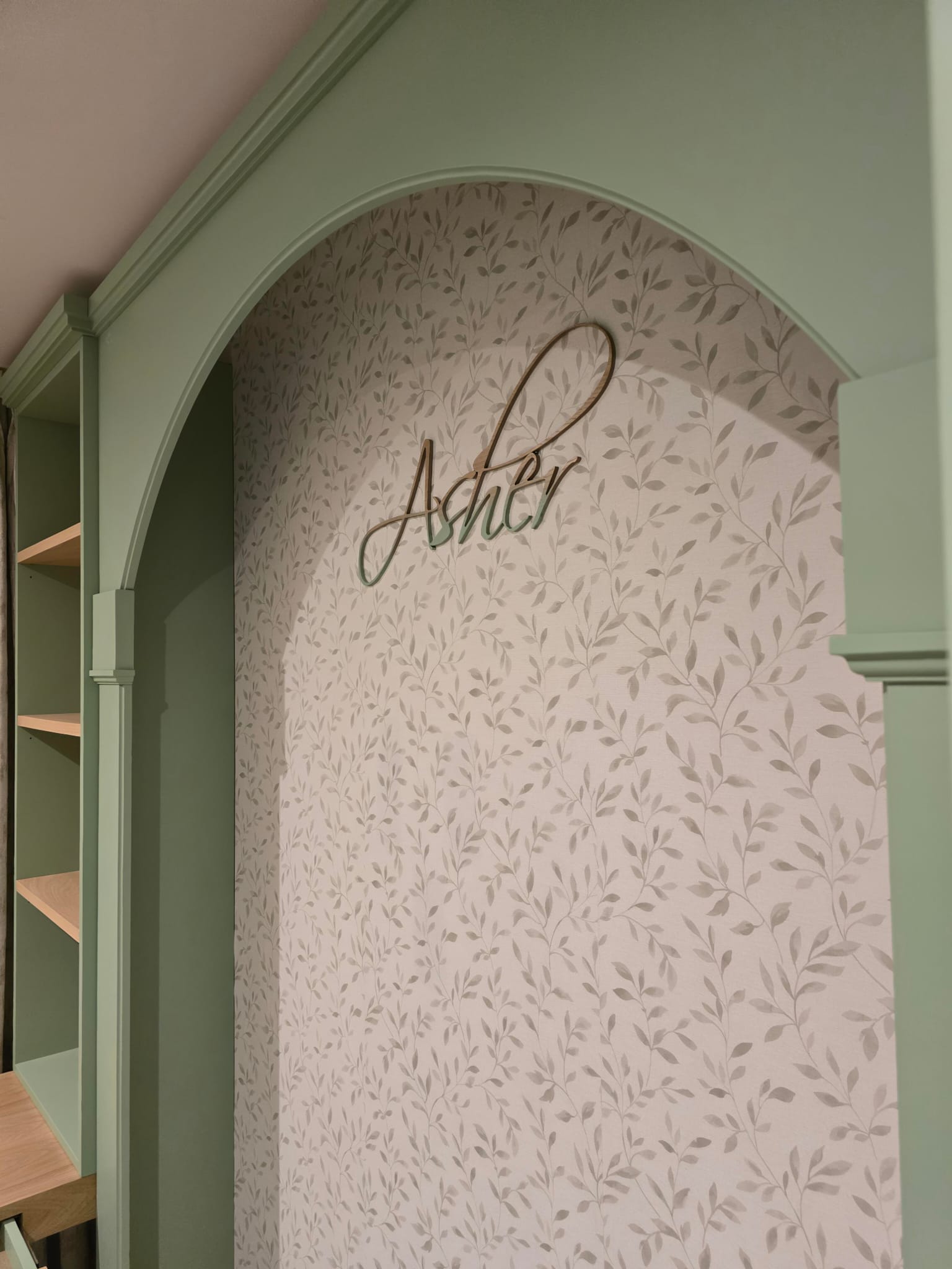 Asher's arched sleeping area with leaf-pattern wallpaper and fitted green joinery