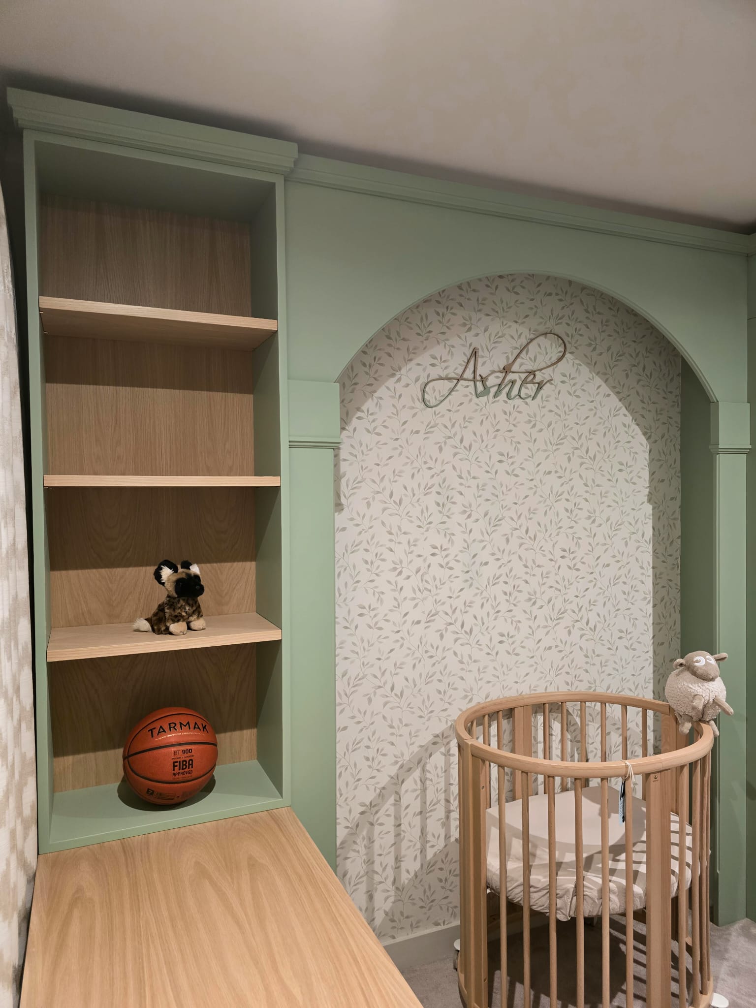 Natural oak shelving and extended desk beside an arched sleeping area in Greenwich