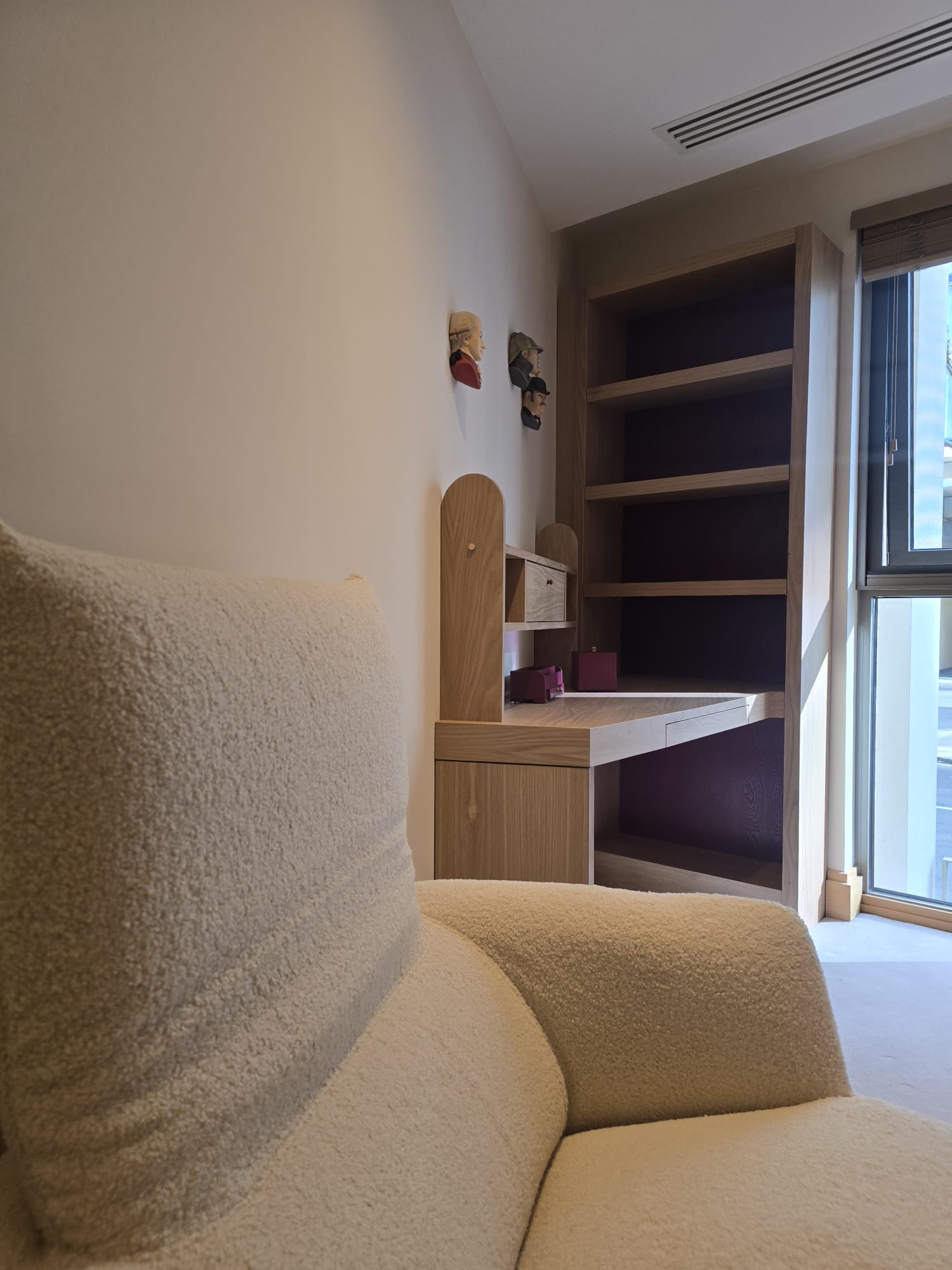 Space-saving oak bookcase and corner desk beside the bedroom window in Westminster