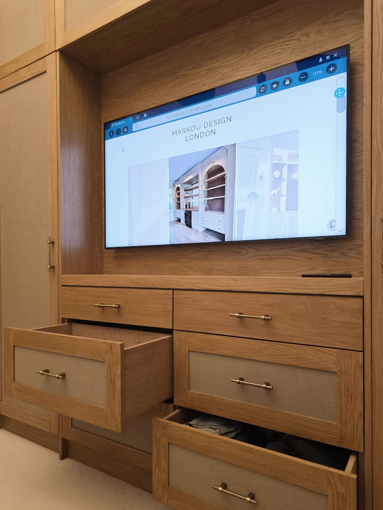 Oak drawer storage with fabric inlays and brass handles in a Holland Park dressing room