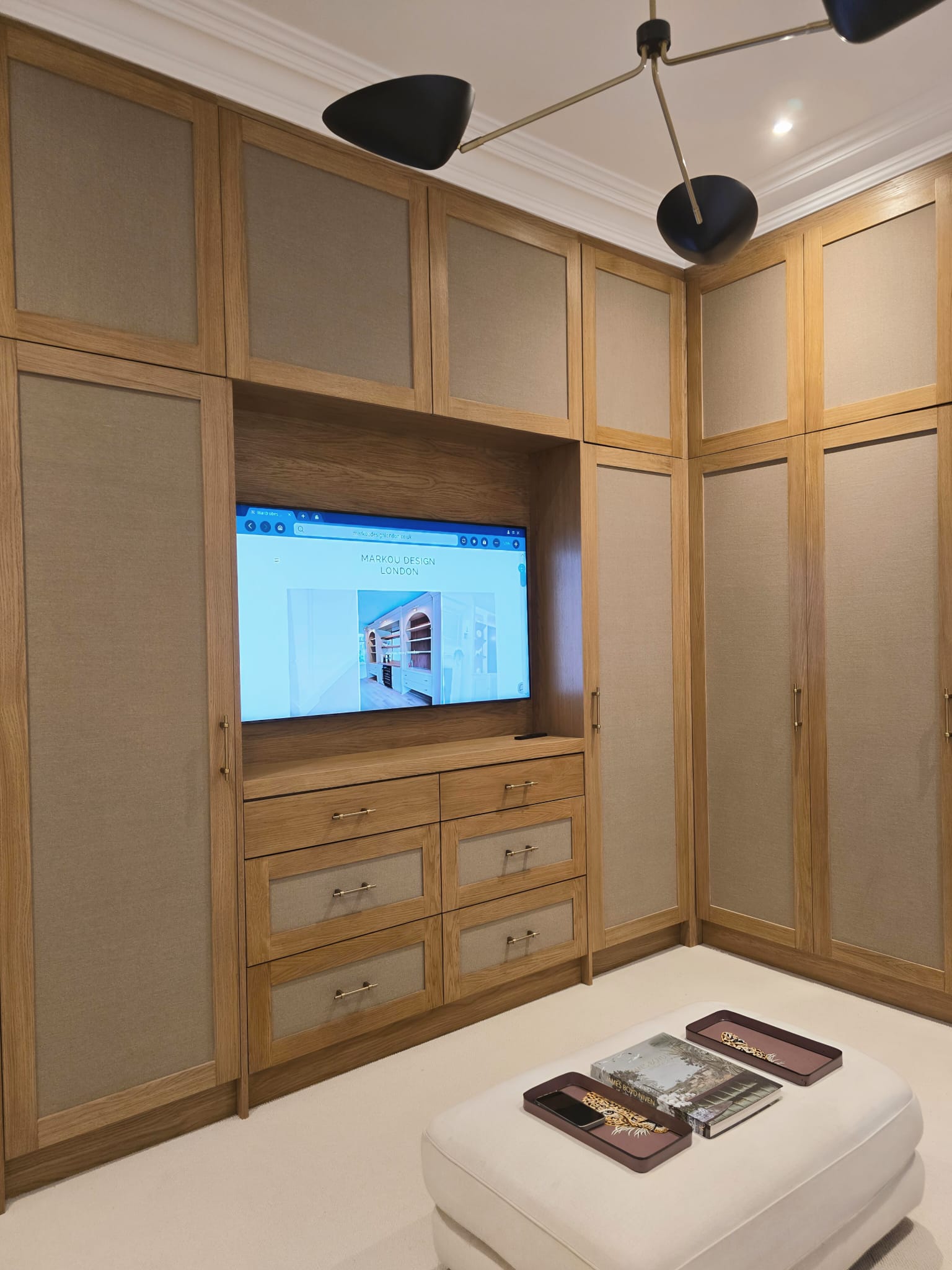 Oak and fabric dressing room wardrobes with an integrated TV unit at Saint Ann's Villas