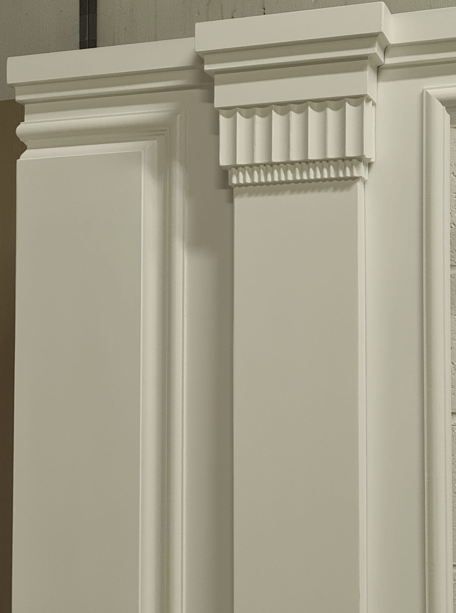Fluted pilaster and layered capital detail on painted wall panelling in Chelsea