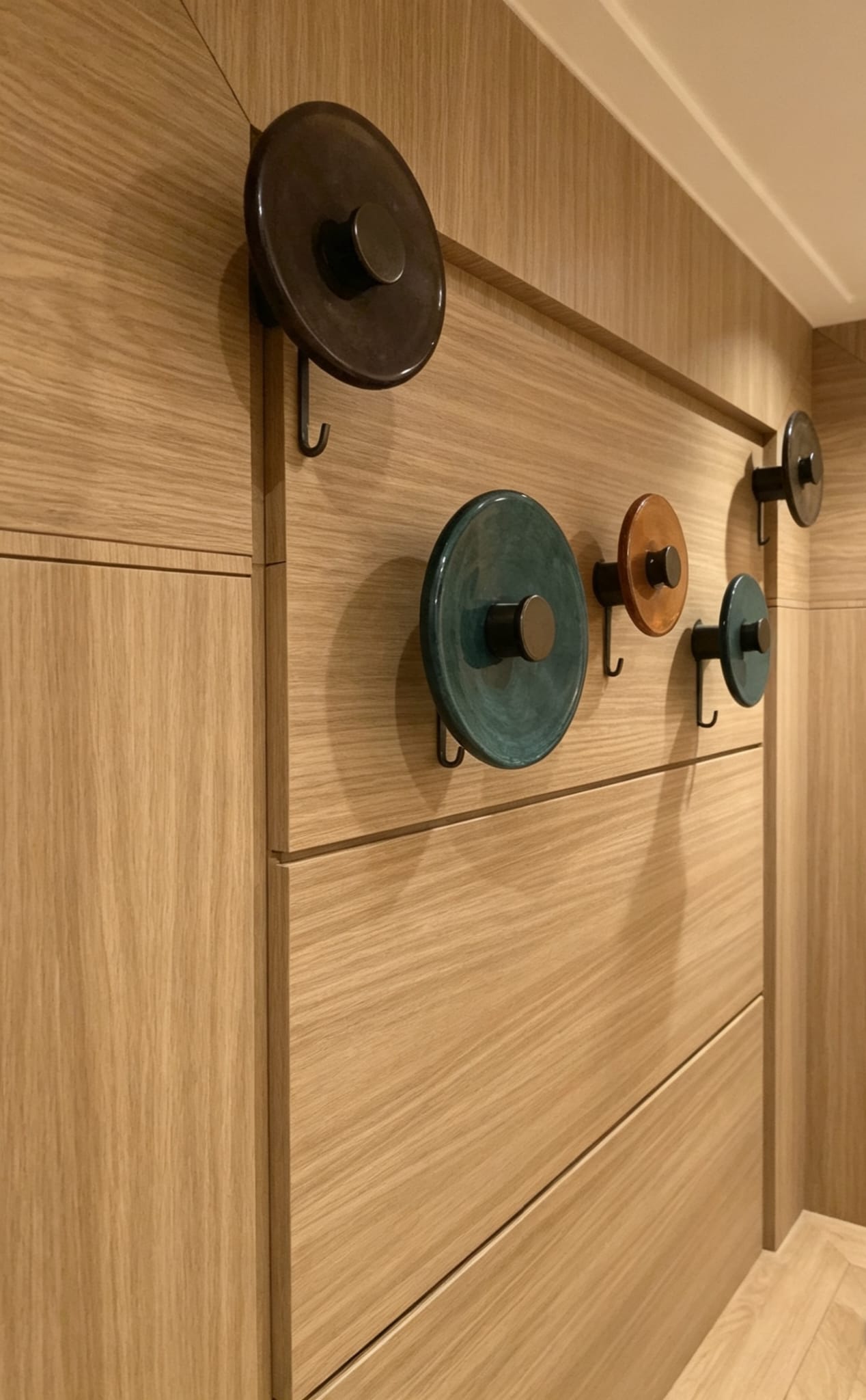 Decorative coat hooks arranged on natural oak veneer wall panelling in Westminster