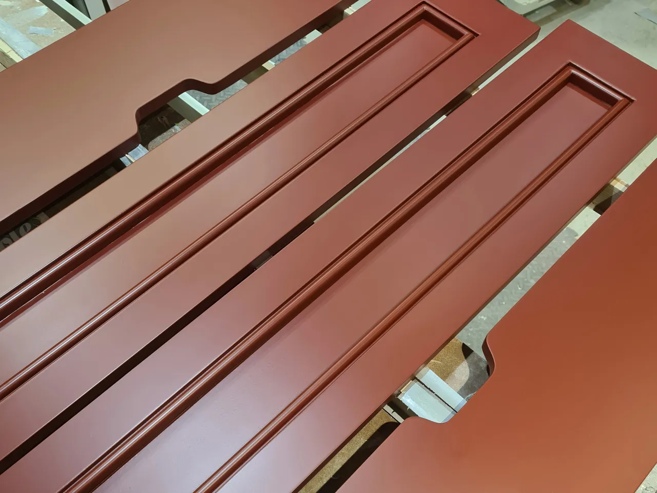 Terracotta spray-painted panelled furniture doors curing in the workshop