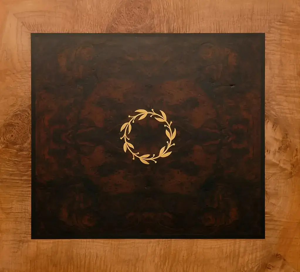 Hand-cut gold laurel wreath marquetry inlay on burr walnut panel