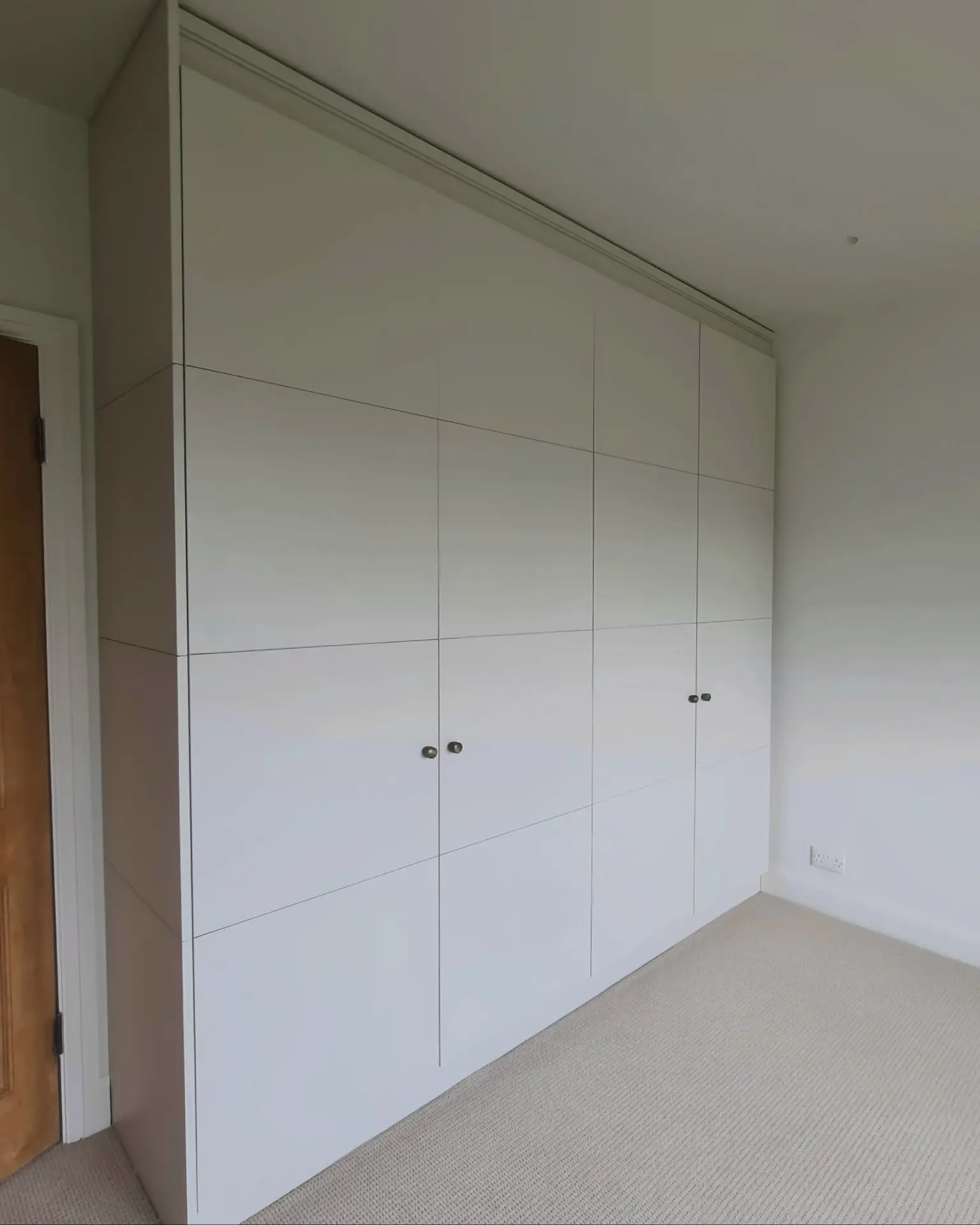 Floor-to-ceiling bespoke fitted wardrobes in a Wimbledon bedroom
