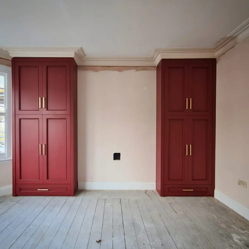 Heritage red fitted wardrobes with brass handles in Victorian period room, Arnos Grove, London