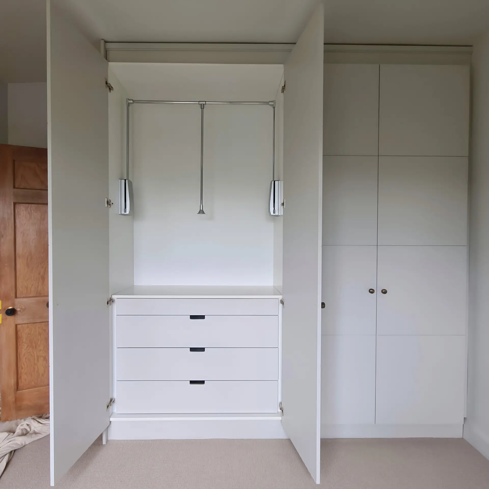 Open fitted wardrobe with pull-down hanging rail and integrated drawers in Wimbledon