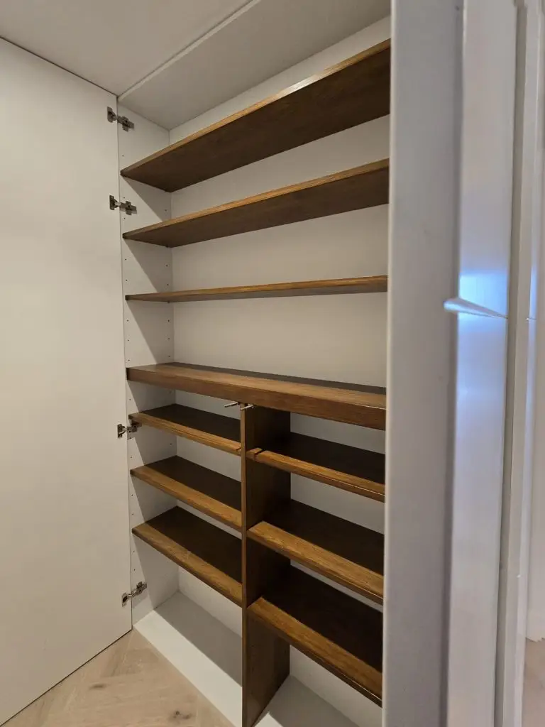 Open concealed hallway cabinet showing tailored oak shoe shelving in Chelsea, London