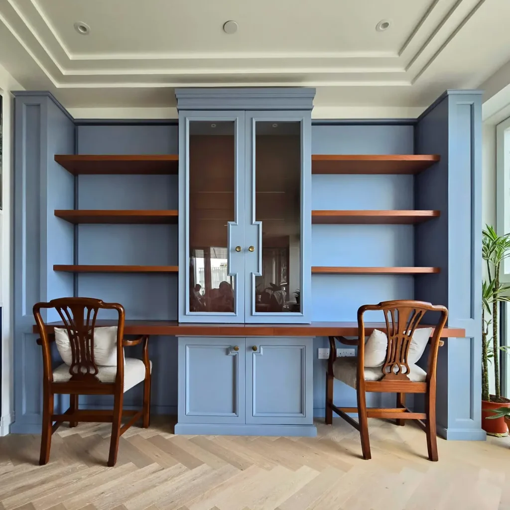 Dusty blue fitted library cabinetry with mahogany shelving in Chelsea Creek, London