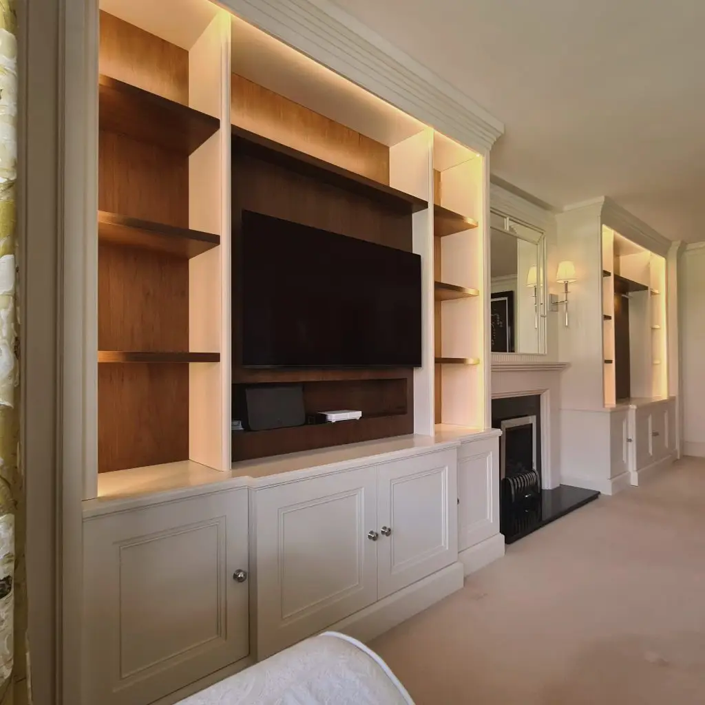 Painted alcove cabinetry and illuminated shelving beside a Ruislip fireplace