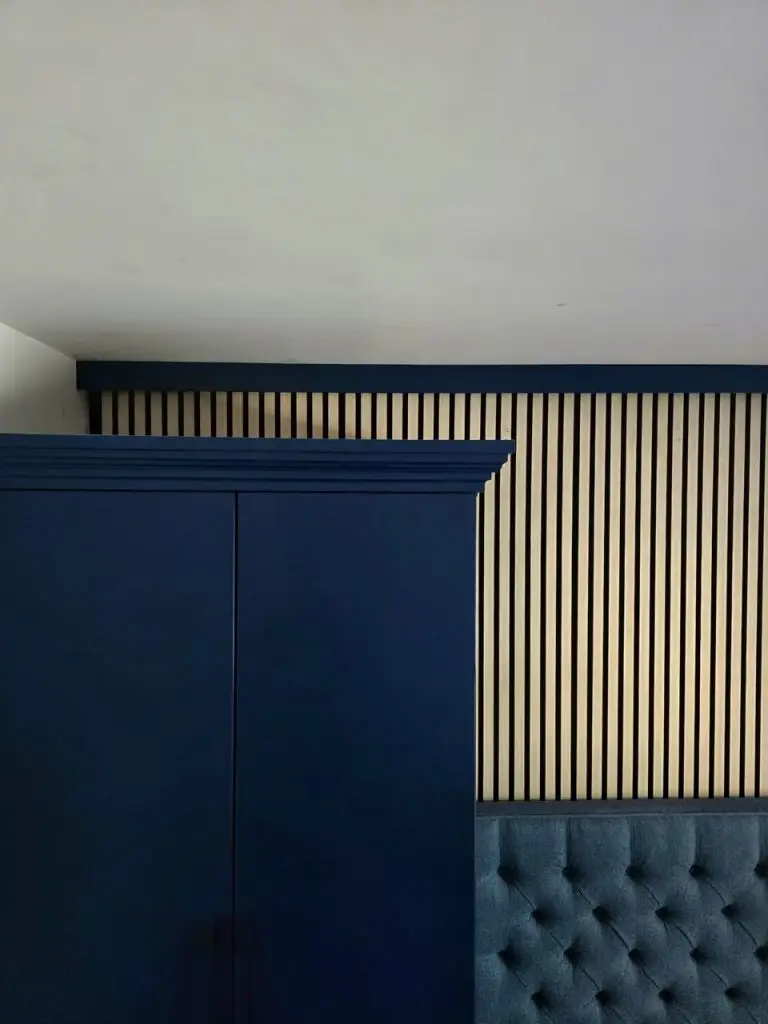 Navy fitted bedroom — wardrobe and slatted feature wall with sloped ceiling