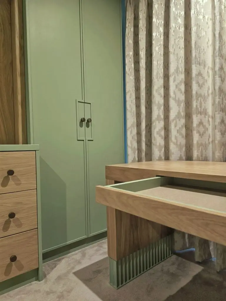 Bespoke sage green nursery — wardrobe with recessed handle detail and integrated dresser